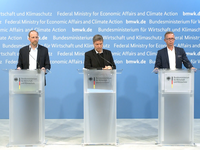 Drei Menschen stehen hinter Transparenten mit dem Logo des Bundesministeriums für Wirtschaft und Klimaschutz. Die Personen scheinen an einer Pressekonferenz teilzunehmen, um über wirtschaftliche und klimatische Themen zu sprechen. Hintergrund ist ein blauer Wandbereich mit wiederholenden Ministeriumsbezeichnungen.