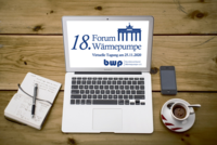 Ein Laptop zeigt das Logo des 18. Forums Wärmepumpe mit dem Datum der virtuellen Tagung am 25.11.2020. Daneben liegen ein Notizbuch und ein Smartphone auf einem Holztisch, sowie eine Tasse Kaffee.