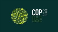 Das Bild zeigt ein stylisiertes, grünes Erdball-Motiv, das mit verschiedenen natürlichen Elementen verziert ist. Darauf steht "COP 28" und "UAE" in klarer, weißer Schrift. Das Design vermittelt ein ökologisches und umweltbewusstes Thema.
