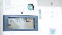 Ein digitaler Stromzähler zeigt einen Verbrauch von 5.299 kWh an. Das Display enthält auch Informationen zu den Zählerdaten und eine Identifikationsnummer. Die Anzeige ist klar und gut lesbar, mit einem hellen, neutralen Hintergrund.