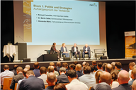 Eine Podiumsdiskussion mit vier Teilnehmern auf der Bühne, die über Politik und Strategien im Bereich Wärmepumpen sprechen. Im Hintergrund ist eine Präsentation an der Wand zu sehen, die den Titel „Block 1: Politik und Strategien“ trägt. Das Publikum sitzt vor der Bühne.