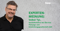 Ein Portrait von Volker Tyc, Geschäftsführer der Öko-Hus Planungs- und Entwicklungsgesellschaft mbH. Er lächelt freundlich und trägt eine schwarze Hemd sowie Brille. Im Hintergrund ist eine graue Wand zu sehen. Der Text „EXPERTENMEINUNG“ wird hervorgehoben.