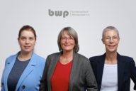 Drei Frauen stehen nebeneinander. Sie lächeln und tragen formelle Kleidung. Im Hintergrund ist das Logo des Bundesverbands Wärmepumpe e.V. sichtbar. Die Atmosphäre wirkt professionell und einladend.