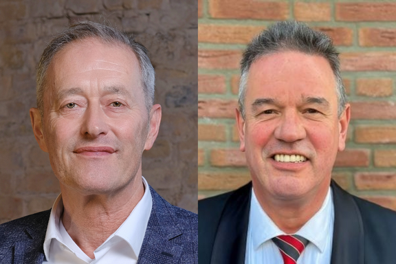 Das Bild zeigt zwei Männer, jeweils zur Hälfte abgebildet. Der Mann links trägt ein helles Hemd und einen dunkelblauen Blazer, während der Mann rechts einen Anzug mit Krawatte trägt. Beide lächeln direkt in die Kamera.