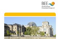 Das Bild zeigt das Reichstagsgebäude in Berlin, ein historisches Gebäude mit einer markanten Kuppel. Im Vordergrund befinden sich Bäume und ein Parkplatz. Der obere Teil des Bildes enthält das Logo des Bundesverbands Erneuerbare Energie e.V.