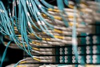 Ein aufgenommener Kabelbaum mit zahlreichen blauen und weißen Kabeln, die in massiven Steckdosen verbunden sind. Die Kabel sind ordentlich angeordnet, zeigen jedoch eine komplexe Anordnung, die oft in Rechenzentren zu finden ist.
