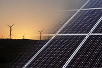 Ein Sonnenuntergang über einer Landschaft mit Windkraftanlagen im Hintergrund. Im Vordergrund sind Solarpanel-Anordnungen sichtbar, die für die Nutzung erneuerbarer Energien stehen. Die Szene strahlt eine Botschaft der Nachhaltigkeit und umweltfreundlicher Energiegewinnung aus.
