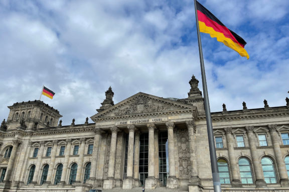 Deutscher Bundestag / Reichstag mit Inschrift: "Dem Deutschen Volke" und Deutschland-Flagge. Im Hintergrund blauer Himmel mit einzelnen Wolken.