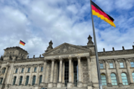 Deutscher Bundestag / Reichstag mit Inschrift: "Dem Deutschen Volke" und Deutschland-Flagge. Im Hintergrund blauer Himmel mit einzelnen Wolken.