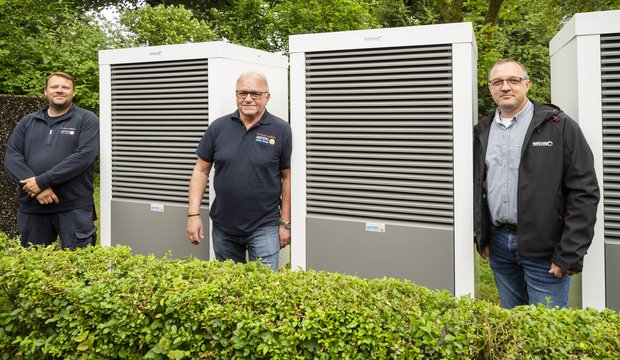 Mitarbeiter der Firmen Meyers OHG und Brötje stehen vor drei Wärmepumpen-Außengeräten
