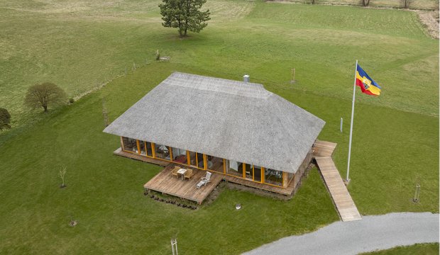 Vorschau von Reetdachhaus mit Rundum-Verglasung heizt mit Wärmepumpe