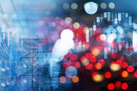 Ein Strommast vor einem verschwommenen Hintergrund mit bunten Lichtern und Grafiken. Die Grafiken zeigen aufsteigende und fallende Kurven, die auf finanzielle Trends hinweisen. Die kühle Farbpalette ist größtenteils blau und rot.