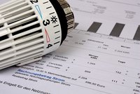 Ein Heizkörperthermostat liegt auf einem Rechnungsdokument. Auf dem Dokument sind verschiedene Zahlen und Beträge aufgeführt, die sich auf den Energieverbrauch und die Kosten beziehen. Der Fokus liegt auf der Abrechnung für den Stromverbrauch.