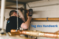 Ein Handwerker, der mit einem Werkzeug an kupfernen Rohren arbeitet. Im Hintergrund ist ein kurzer Schriftzug „Tag des Handwerks“ zu sehen.