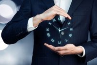 Ein Mann in einem Anzug hält mit beiden Händen eine schwebende Uhr, auf der die römischen Ziffern abgebildet sind. Die Uhr scheint in seiner Hand zu leuchten und symbolisiert die Kontrolle über die Zeit. Hintergrund ist unscharf und vage.