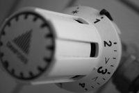 Ein Heizkörperthermostat in Nahaufnahme. Der Drehknopf hat Markierungen von 1 bis 5 sowie eine Stern- und eine Pfeilmarkierung. Die Skala zeigt unterschiedliche Wärmeeinstellungen an. Die Farbe des Thermostats ist hauptsächlich weiß mit schwarzen Ziffern und einem grafischen Logo.