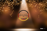 Ein runder Preis mit der Aufschrift „Deutscher Award für Nachhaltigkeitsprojekte 2026“ und dem Wort „Unternehmer“ in der Mitte. Der Hintergrund zeigt eine Bühnenbeleuchtung mit goldenen Konfetti, die eine festliche Atmosphäre schaffen.