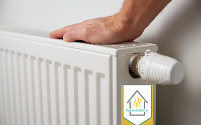 Eine Hand dreht an einem Heizkörperthermostat. Der Heizkörper ist weiß und an einer Wand angebracht. In der Ecke befindet sich ein Logo mit dem Text „#WocheDerWärme“.