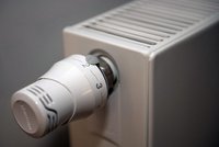 Ein Heizkörper mit einem Thermostat. Der Thermostat ist weiß und zeigt Zahlen von 1 bis 5 an. Er ist auf etwa 2 eingestellt. Der Heizkörper hat eine moderne, rechteckige Form und ist an einer Wand montiert.