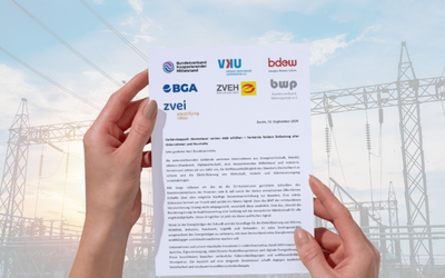 Zwei Hände halten ein Dokument mit Logos von verschiedenen Organisationen, vor einem Hintergrund von Stromleitungen und einem Himmel. Das Dokument enthält Informationen über die Zusammenarbeit der Verbände im Energiebereich.