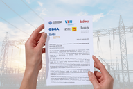 Zwei Hände halten ein Dokument mit Logos von verschiedenen Organisationen, vor einem Hintergrund von Stromleitungen und einem Himmel. Das Dokument enthält Informationen über die Zusammenarbeit der Verbände im Energiebereich.