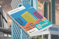 Ein offenes Buch mit dem Titel "DENA-GEBÄUDEREPORT 2026" auf einem farbenfrohen Cover, das abstrakte Gebäude darstellt. Im Hintergrund sind moderne Wolkenkratzer sichtbar. Das Bild vermittelt den Eindruck von städtischer Architektur und Gebäudeanalysen.